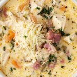 Bowl of creamy Chicken Cordon Bleu Soup topped with shredded Swiss cheese and fresh parsley