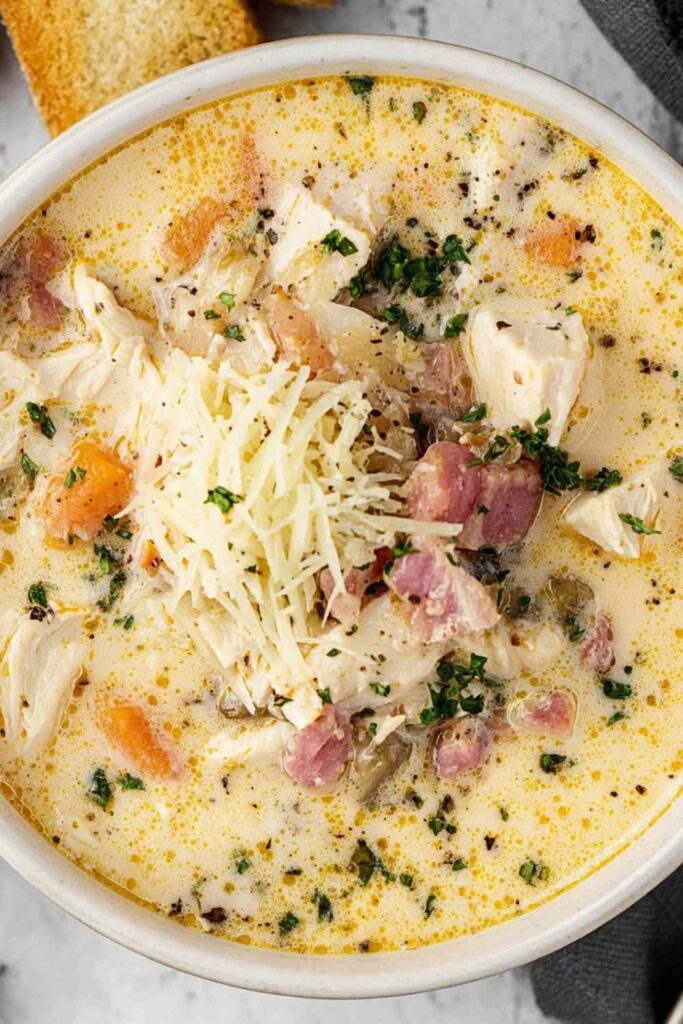 Bowl of creamy Chicken Cordon Bleu Soup topped with shredded Swiss cheese and fresh parsley