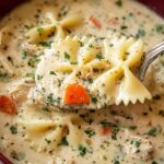 Creamy chicken alfredo soup in a white bowl topped with freshly grated Parmesan and chopped parsley
