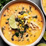 Creamy chicken poblano soup in a bowl garnished with fresh cilantro and lime wedges
