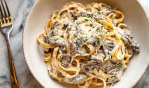 Creamy garlic butter chicken bowtie pasta in a skillet topped with fresh parsley and Parmesan cheese