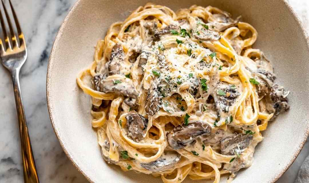Creamy garlic butter chicken bowtie pasta in a skillet topped with fresh parsley and Parmesan cheese