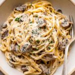 Creamy garlic butter chicken bowtie pasta in a skillet topped with fresh parsley and Parmesan cheese