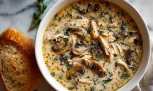 Creamy rotisserie chicken mushroom soup in a white bowl garnished with fresh parsley
