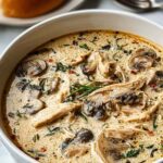 Creamy rotisserie chicken mushroom soup in a white bowl garnished with fresh parsley