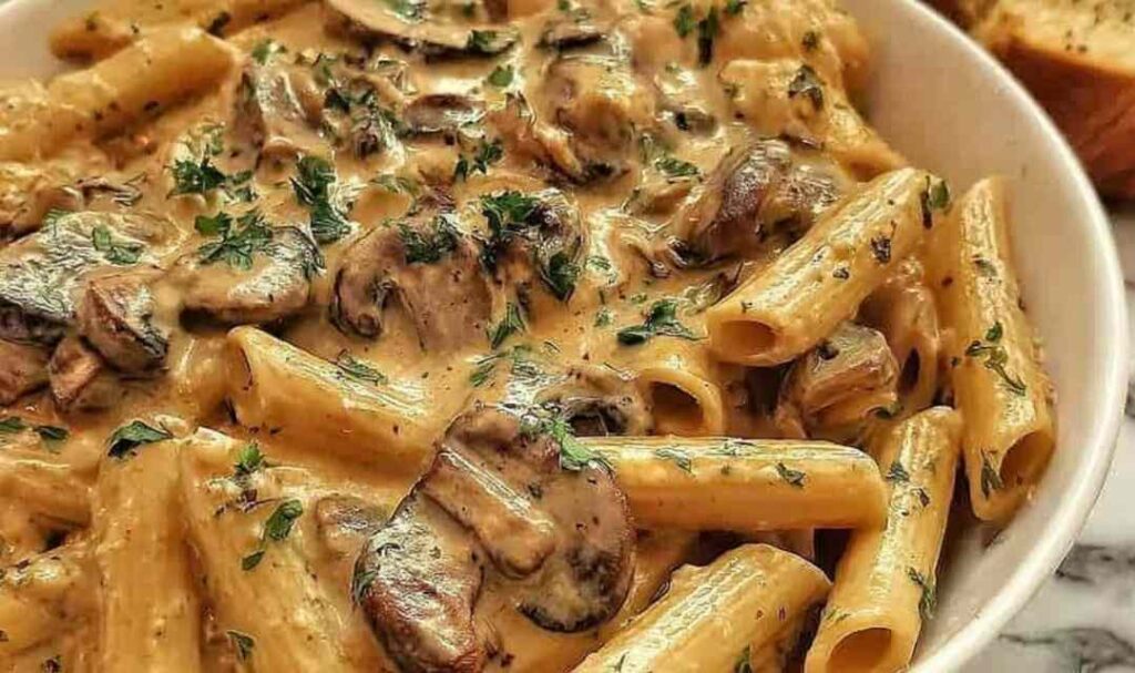 Creamy Tuscan mushroom pasta skillet with spinach and sun-dried tomatoes in a large pan