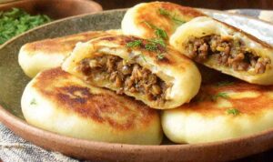 Crispy stuffed potato cakes with meat and mushrooms served on a plate with sour cream