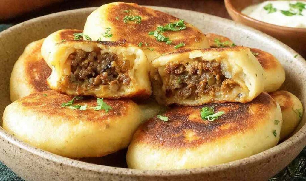 Crispy stuffed potato cakes with meat and mushrooms served on a plate with sour cream