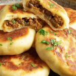 Crispy stuffed potato cakes with meat and mushrooms served on a plate with sour cream