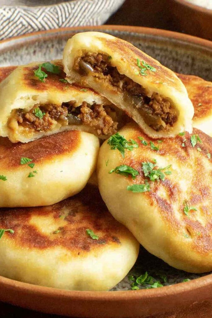 Crispy stuffed potato cakes with meat and mushrooms served on a plate with sour cream