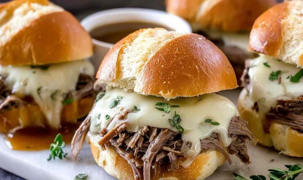 Crockpot French dip sandwiches with shredded beef and melted Provolone on toasted hoagie rolls served with au jus dipping sauce