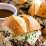 Crockpot French dip sandwiches with shredded beef and melted Provolone on toasted hoagie rolls served with au jus dipping sauce