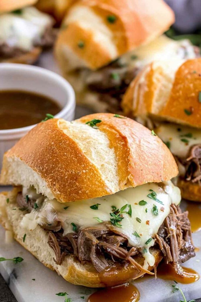 Crockpot French dip sandwiches with shredded beef and melted Provolone on toasted hoagie rolls served with au jus dipping sauce