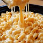 Creamy crockpot mac and cheese served in a white bowl with melted cheddar cheese