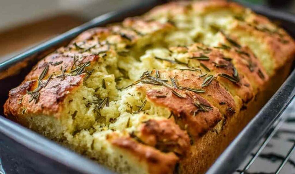 Sliced dill pickle bread loaf on a wooden cutting board with fresh dill and pickle chips