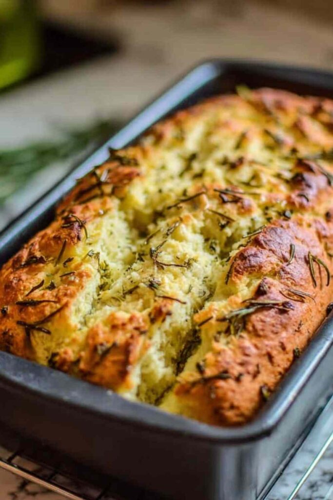 Sliced dill pickle bread loaf on a wooden cutting board with fresh dill and pickle chips