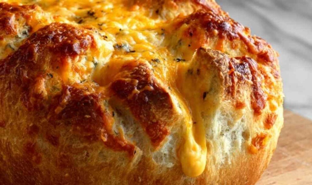 Dutch oven cheddar bread loaf with golden crust sliced open to show cheesy interior