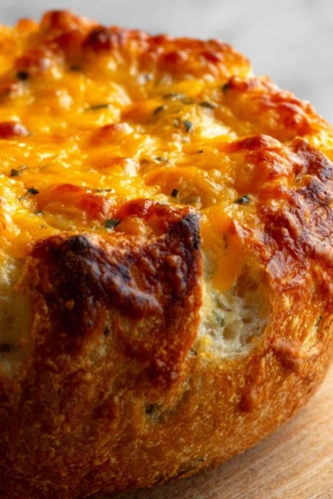 Dutch oven cheddar bread loaf with golden crust sliced open to show cheesy interior