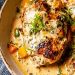 Easy baked queso chicken in a white baking dish topped with creamy melted cheese and fresh cilantro