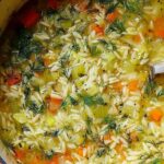 Bowl of easy orzo leek and dill soup garnished with fresh dill on a wooden table