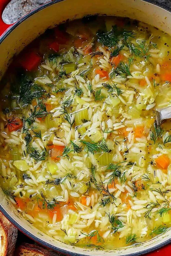 Bowl of easy orzo leek and dill soup garnished with fresh dill on a wooden table