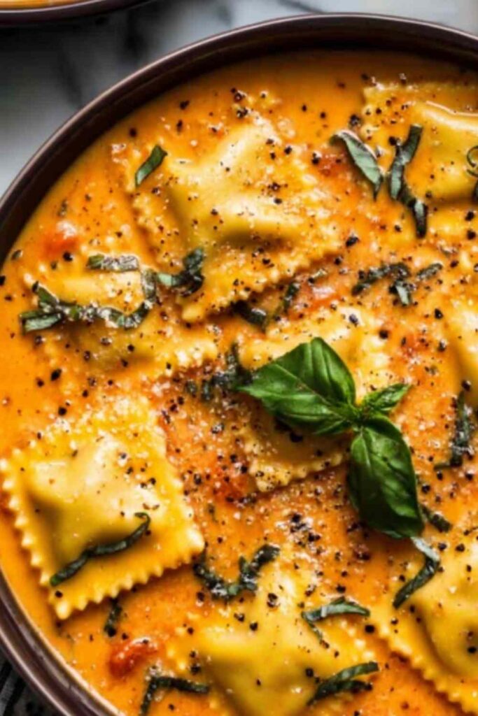 Easy Tuscan ravioli soup served in a white bowl topped with Parmesan cheese and fresh spinach