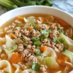 Egg roll soup with ground beef, cabbage, and sesame seeds in a white bowl