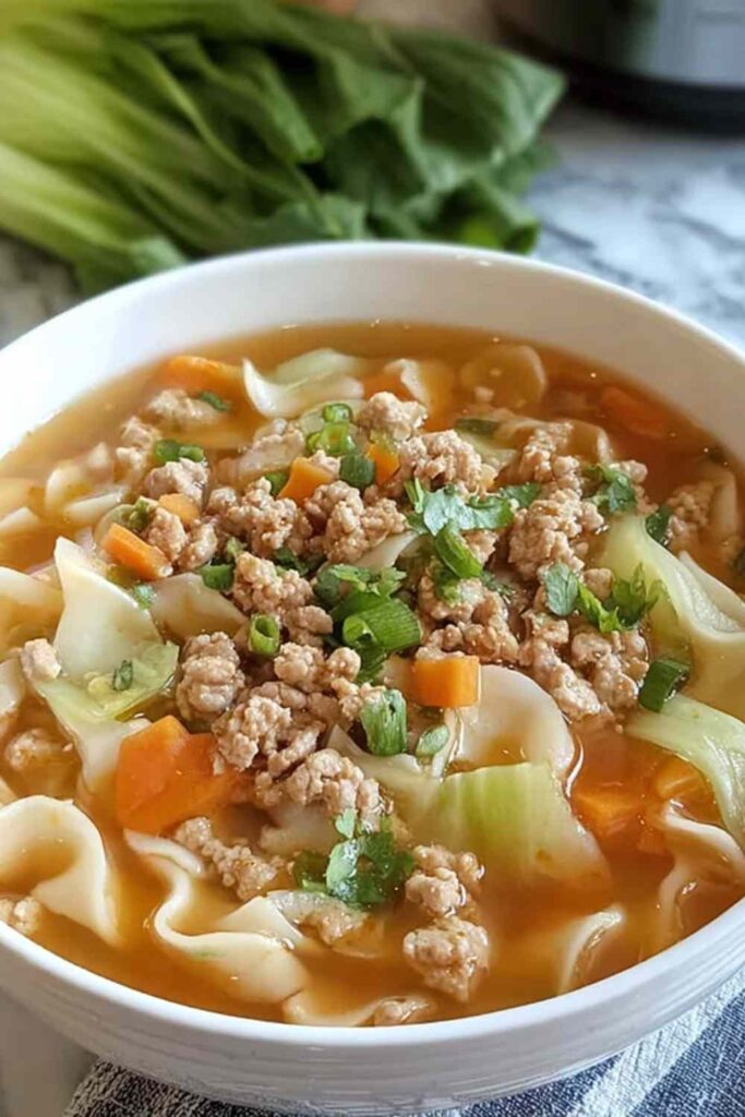 Egg roll soup with ground beef, cabbage, and sesame seeds in a white bowl