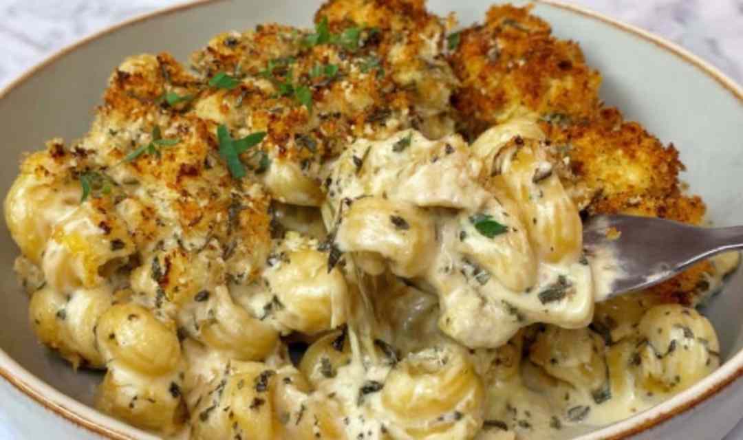 Creamy French onion soup pasta in a skillet topped with fresh parsley and melted Gruyere cheese