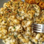 Creamy French onion soup pasta in a skillet topped with fresh parsley and melted Gruyere cheese