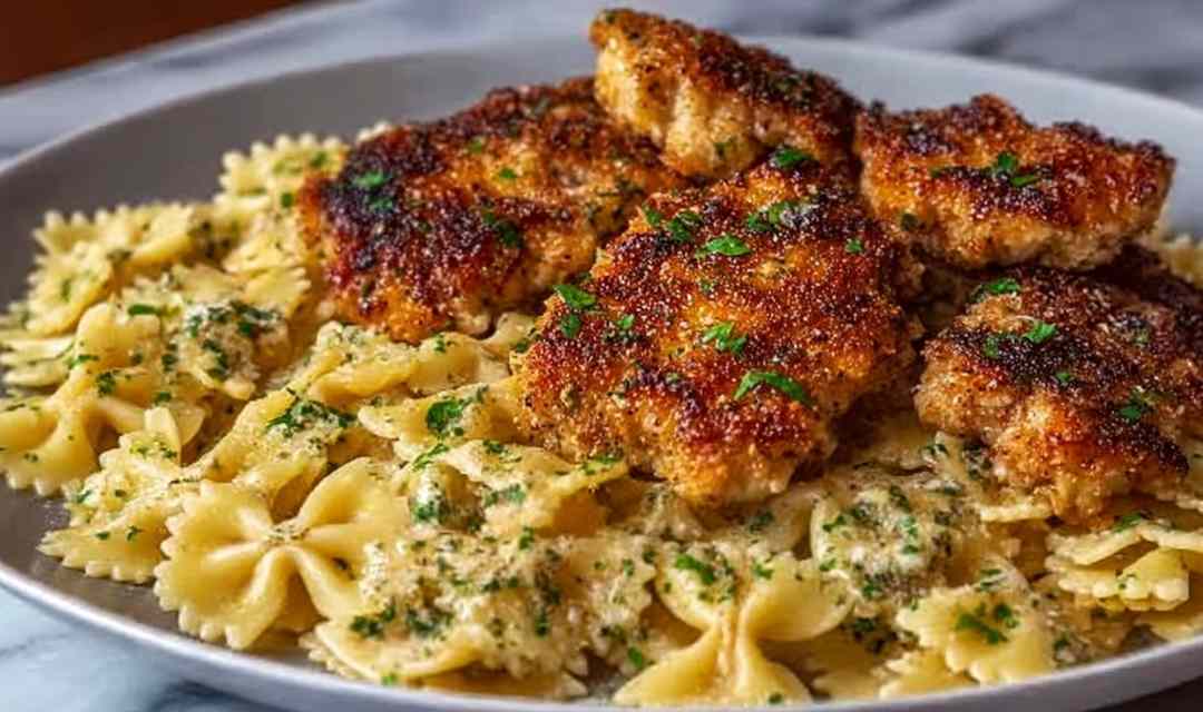 Creamy garlic butter chicken bowtie pasta in a skillet topped with fresh parsley and Parmesan cheese