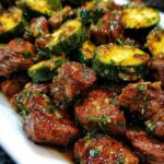 Garlic butter steak bites with zucchini in a cast-iron skillet garnished with fresh parsley