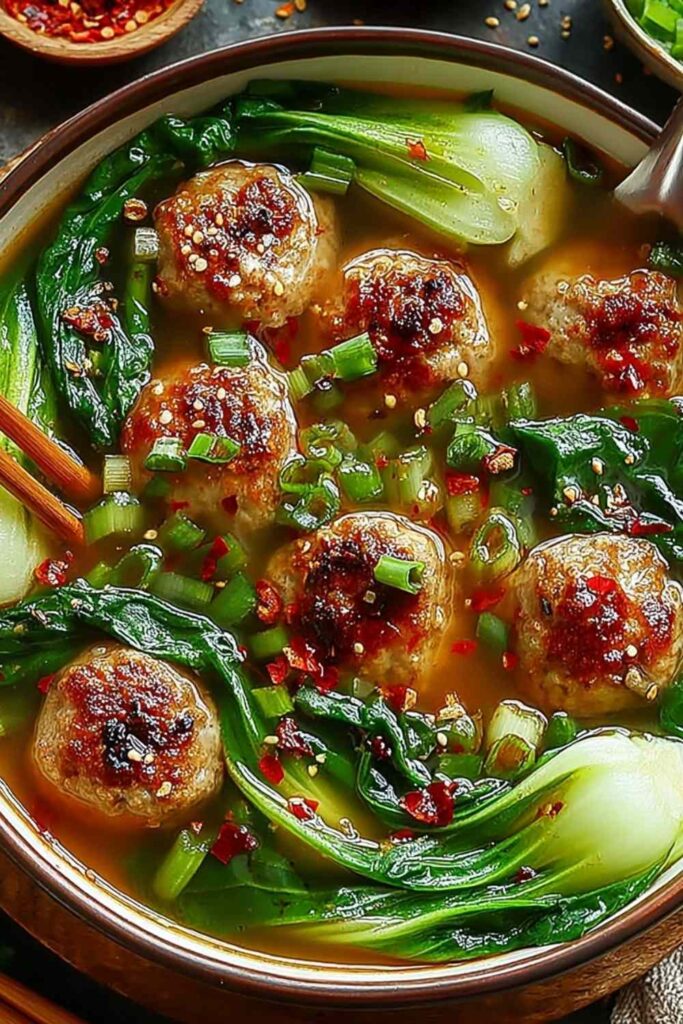 Ginger chicken meatball soup in a white bowl with baby bok choy and crispy wonton strips