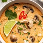 Grilled Greek chicken tenders on a white plate garnished with fresh dill and lemon slices