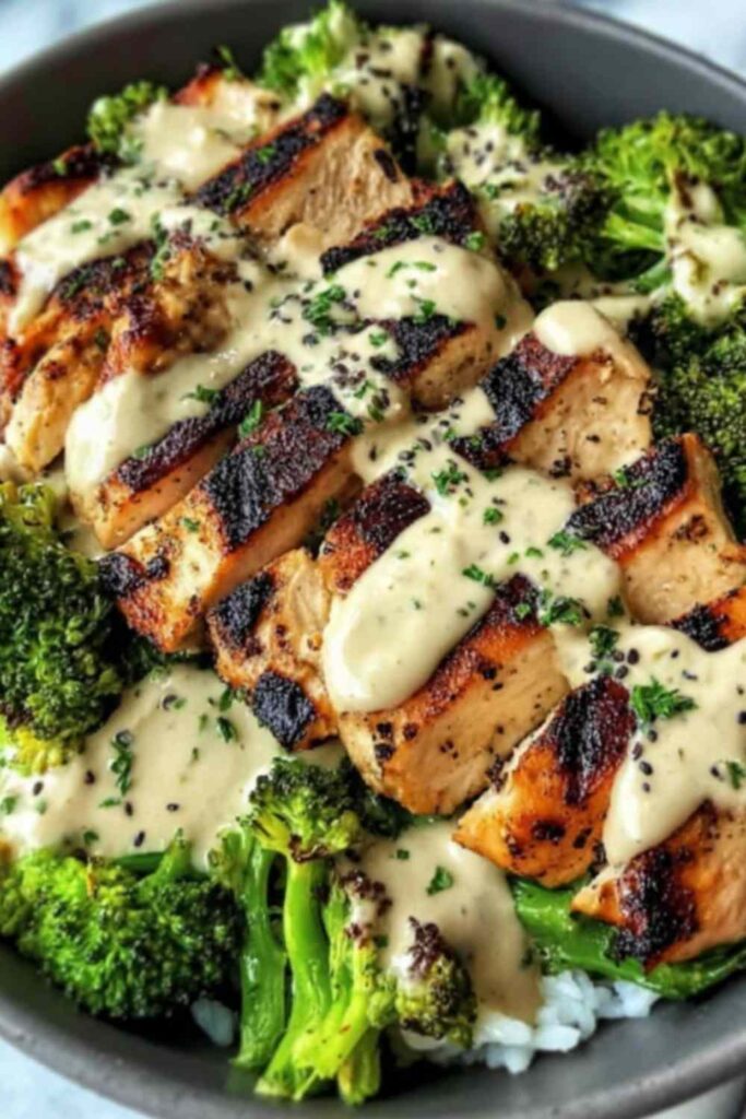 Grilled chicken broccoli bowls with creamy garlic sauce served over white rice with fresh parsley garnish