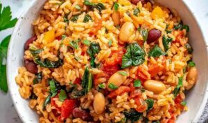 Mediterranean rice and beans in a skillet with fresh parsley, dill, and lemon