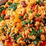 Mediterranean rice and beans in a skillet with fresh parsley, dill, and lemon