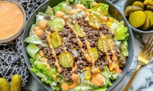 High-protein cheeseburger bowl with seasoned ground beef, cheddar cheese, pickles, tomatoes, and creamy cottage cheese sauce