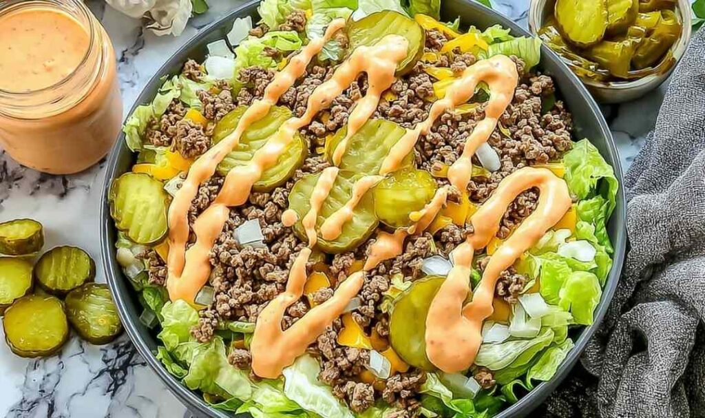 High-protein cheeseburger bowl with seasoned ground beef, cheddar cheese, pickles, tomatoes, and creamy cottage cheese sauce