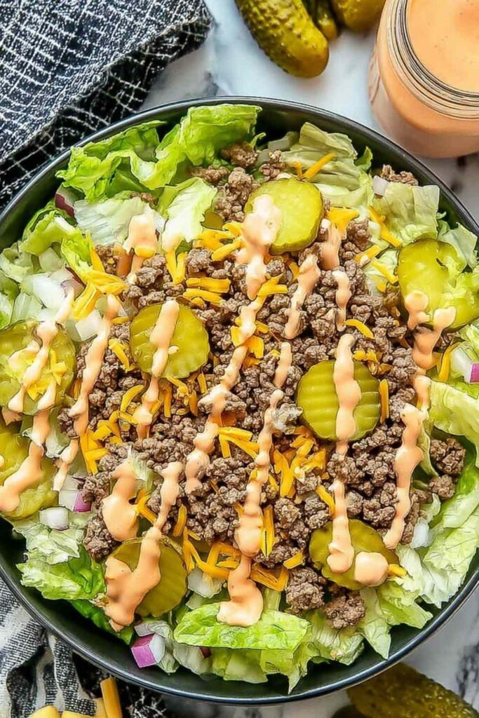 High-protein cheeseburger bowl with seasoned ground beef, cheddar cheese, pickles, tomatoes, and creamy cottage cheese sauce
