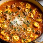 Homemade lasagna soup with tortellini topped with ricotta and melted mozzarella in a white bowl