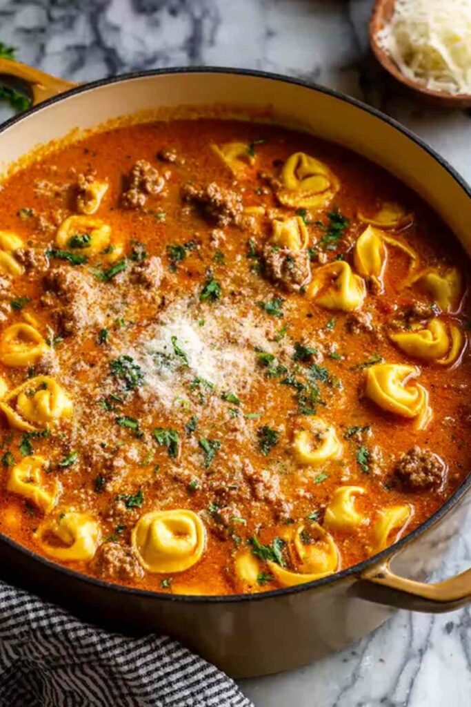Homemade lasagna soup with tortellini topped with ricotta and melted mozzarella in a white bowl