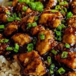 Honey BBQ chicken rice in a skillet topped with sliced green onions and melted cheddar cheese