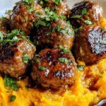 Juicy beef meatballs with creamy sweet potato mash drizzled with bourbon maple pan sauce on a white plate