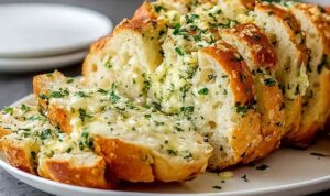 Sliced Italian herb and cheese bread on a wooden cutting board showing melted mozzarella filling