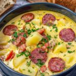 Creamy kielbasa potato soup in a white bowl topped with fresh chopped parsley