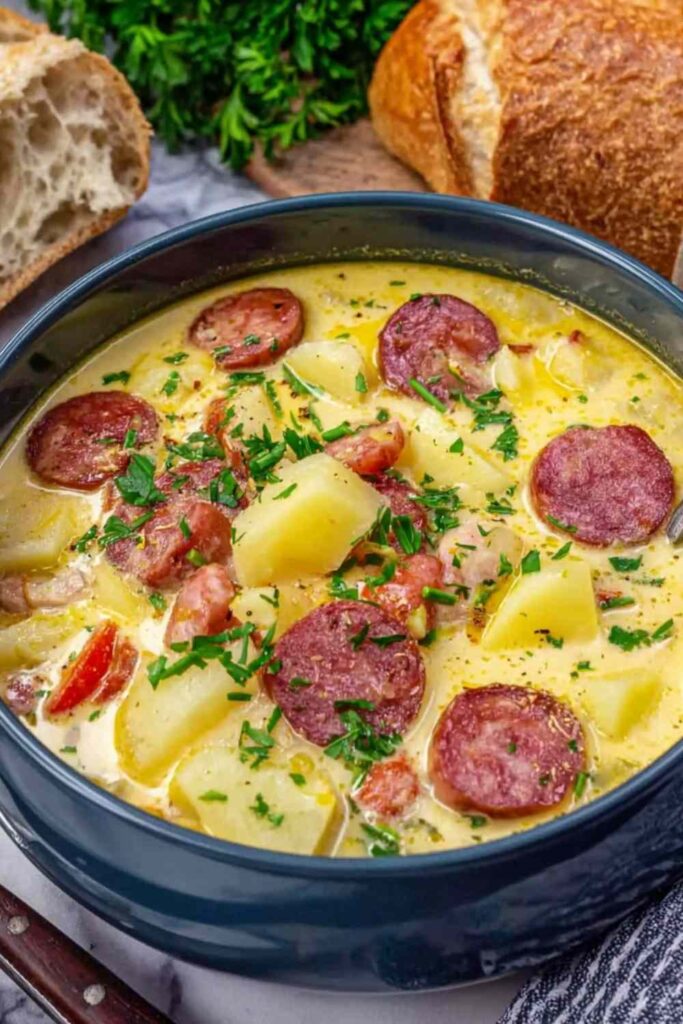 Creamy kielbasa potato soup in a white bowl topped with fresh chopped parsley
