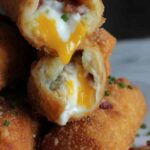 Crispy loaded mashed potato egg rolls on a wire rack garnished with sliced green onions
