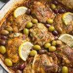 Mediterranean chicken with lemons and olives in a cast iron skillet garnished with fresh parsley