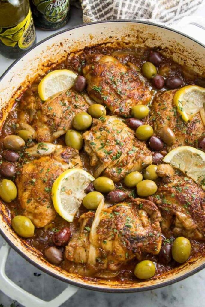 Mediterranean chicken with lemons and olives in a cast iron skillet garnished with fresh parsley